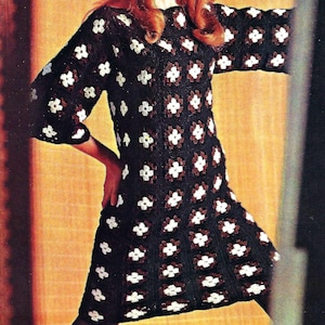 May include: A woman wearing a black and white crochet dress with a floral pattern. The dress has a scoop neckline and three-quarter sleeves. The woman has long red hair and is wearing a headband.