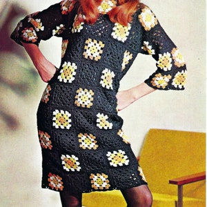 May include: A black crochet dress with square floral patterns in yellow, orange, and white. The dress has long sleeves and a knee-length hemline. The model is wearing a yellow headband.