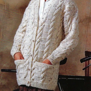 May include: A white cable knit cardigan with a button front and two patch pockets. The cardigan is worn over a white collared shirt.