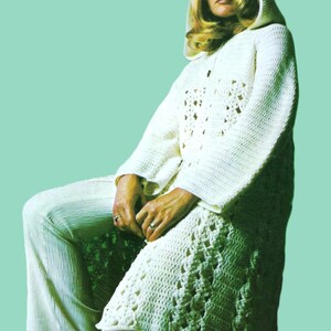 May include: A white crocheted hooded cardigan with a lacy pattern. The cardigan is worn over a pair of white pants.