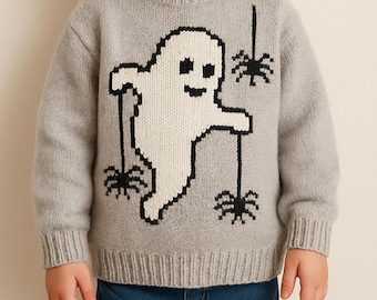 May include: A light gray sweater featuring a white ghost and black spiders. The ghost has a pixelated design, and the spiders hang from black strings. The sweater is worn by a young child, and is paired with blue jeans.