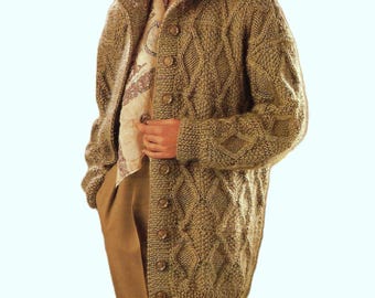 May include: A long, olive green knitted cardigan with a cable knit pattern. The cardigan has a button-up front, a shawl collar, and long sleeves. The model is wearing a patterned scarf and brown pants.