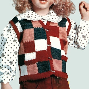 Può includere: Un bambino indossa un gilet lavorato a maglia patchwork nei toni del rosso, verde, bianco e rosa. Il gilet ha una chiusura con bottoni ed è sovrapposto a una camicetta bianca con colletto e maniche a stampa paisley. Il bambino indossa anche pantaloni di velluto a coste rossi.