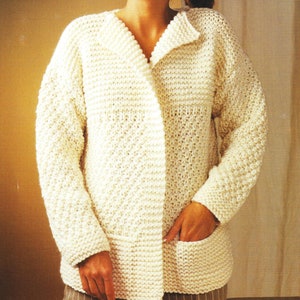 Op de afbeelding: Een wit gebreid vest met een V-hals en één zak op de voorkant.