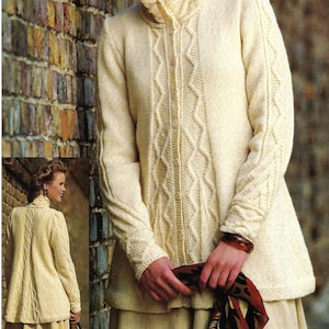May include: A cream-colored knitted cardigan with a cable knit pattern and button closure. The cardigan has a high collar and long sleeves. The model is wearing the cardigan with a scarf and a bracelet.