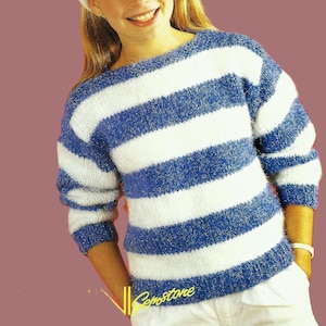 May include: A girl wearing a white headband and a blue and white striped sweater with silver glitter. The sweater has long sleeves and a round neckline.