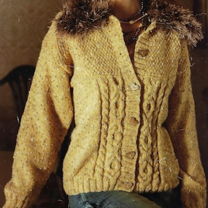 May include: A yellow knitted cardigan with a faux fur collar and heart-shaped buttons. The cardigan has a cable knit pattern and is made with a speckled yarn.