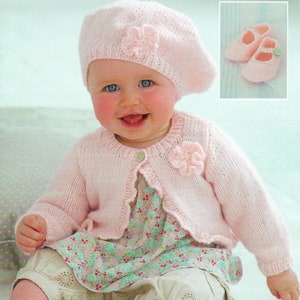 May include: A pink knitted cardigan with a flower detail on the front, worn by a baby with a pink knitted beret and a floral print dress.