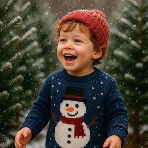 Puede incluir: Un ni&ntilde;o lleva un su&eacute;ter azul marino con un dise&ntilde;o de mu&ntilde;eco de nieve y un gorro de punto rojo. El su&eacute;ter presenta un mu&ntilde;eco de nieve con sombrero de copa negro, bufanda roja y nariz de zanahoria. Copos de nieve blancos dispersos.