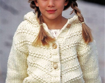 Könnte beinhalten: Ein weißer Strickcardigan mit Kapuze und Knopfleiste. Der Cardigan hat ein strukturiertes Muster und wird von einem jungen Mädchen mit blonden Haaren getragen.