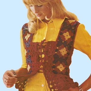May include: A burgundy crochet vest with a floral pattern in shades of cream, navy, and brown. The vest has a square neckline and a lace-up front. The garment is worn over a yellow collared shirt.