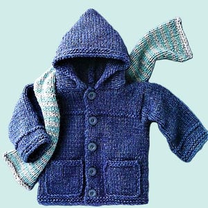 Puede incluir: Una chaqueta de punto azul con capucha y una bufanda a juego. La chaqueta tiene cierre de botones y dos bolsillos.