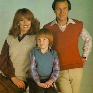 Può includere: Una famiglia di tre persone che indossano gilet di maglia. La donna indossa un gilet beige, l'uomo indossa un gilet rosso e il bambino indossa un gilet blu.