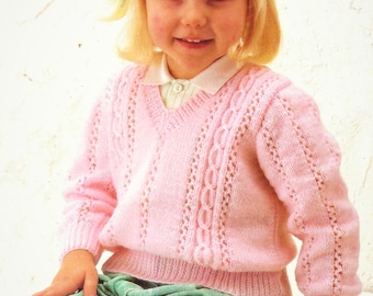 May include: A pink knitted sweater with a v-neck and cable knit detail. The sweater is worn by a young girl with blonde hair and a white collar.