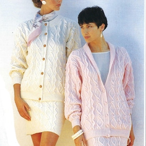 May include: Two women wearing matching knitted sweater sets. The woman on the left is wearing a white set with a scarf, while the woman on the right is wearing a pink set.