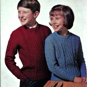 May include: Two children wearing knitted sweaters with cable knit patterns. The boy is wearing a red sweater and the girl is wearing a blue sweater.