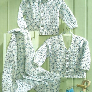 May include: Two white and blue knitted cardigans with button closures and a white and blue knitted baby blanket.
