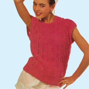 Può includere: Un top senza maniche rosa lavorato a maglia con un motivo strutturato. Il top è abbinato a pantaloncini bianchi e una fascia bianca. L'immagine è su uno sfondo azzurro. Il testo "cotton DK" è visibile nell'angolo in alto a sinistra.