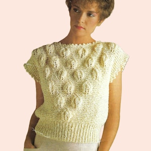 Peut inclure: Un haut en tricot de couleur crème à manches courtes et un motif texturé de petites feuilles.