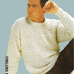 Könnte beinhalten: Ein weißer Strickpullover mit einem strukturierten Muster. Der Pullover hat einen Rundhalsausschnitt und lange Ärmel. Das Model trägt den Pullover mit einer rot-schwarzen Karohosen.