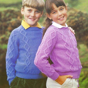 May include: A blue long-sleeved knit jumper with a diamond cable pattern and a yellow collared shirt underneath, paired with a purple long-sleeved knit cardigan featuring a diamond cable pattern and a white collared shirt underneath.