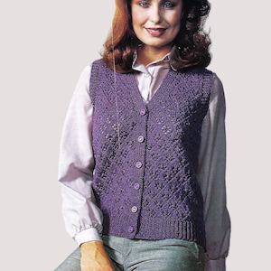 May include: A purple knitted waistcoat with a V-neck and button fastening. The waistcoat has a lacy pattern and is worn over a white button-down shirt.