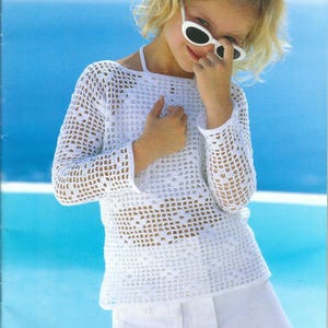 Puede incluir: Una niña pequeña con un top blanco de ganchillo y una falda blanca. Lleva gafas de sol y tiene el pelo recogido hacia atrás.