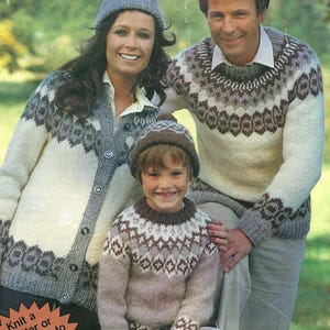 Puede incluir: Familia con jerséis y gorros de punto a juego. Los jerséis tienen un patrón geométrico en tonos blancos, grises y marrones. La imagen incluye el texto "Spun in Great Britain."