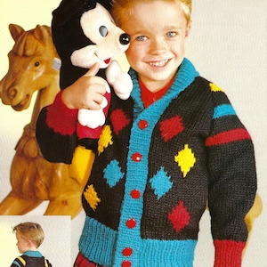 May include: A black cardigan with a colourful diamond pattern, red buttons, and red, yellow, and blue stripes on the sleeves. The cardigan is worn by a young boy holding a Mickey Mouse plush toy.