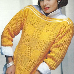 May include: A yellow knitted sweater with a white trim and a geometric pattern. The sweater has a boat neck and long sleeves.