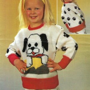 Könnte beinhalten: Ein weißer Strickpullover mit einem roten und weißen Streifen am Saum. Der Pullover zeigt vorne ein schwarz-weißes Hundemuster und schwarze Pfotenabdrücke an den Ärmeln. Die Rückseite des Pullovers hat schwarze Pfotenabdrücke.