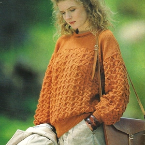 May include: A woman wearing a brown knitted sweater with a geometric pattern, beige corduroy pants, and a brown leather shoulder bag.