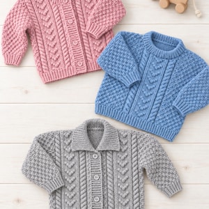 May include: Three knitted jumpers in pink, blue, and grey. The pink and grey jumpers are button-down cardigans with collars, while the blue jumper is a pullover. All feature textured cable knit patterns with bobble details and ribbed cuffs.