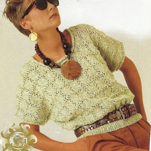 May include: A woman wearing a light green crocheted top with a brown wooden pendant necklace and a brown leather belt with metal accents. She is wearing sunglasses and has short blonde hair.