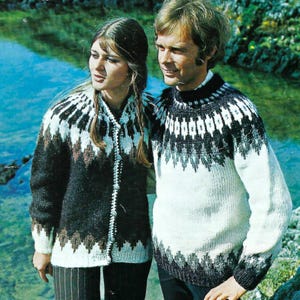 May include: A couple in matching patterned sweaters. The sweaters have a black, white, and brown geometric design around the yoke and cuffs. The woman wears a cardigan with a button closure, while the man wears a crew neck sweater. They are near a body of water.