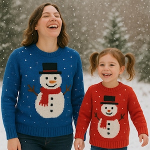 May include: A woman and a child are wearing matching snowman jumpers. The adult's jumper is blue with a white snowman design, a black hat, and a red scarf. The child's jumper is red with a similar snowman design. Snowflakes fall in the background.