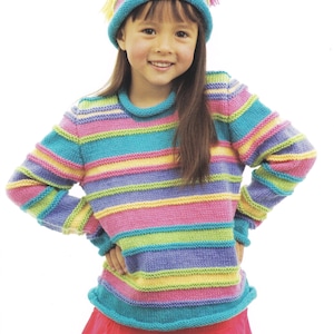 以下が含まれることがあります： カラフルなストライプのセーターとそれに合わせたストライプの帽子をかぶった若い人。セーターと帽子はピンク、ブルー、グリーン、イエローなど、さまざまな色で編まれています。