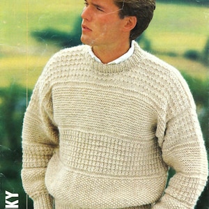 May include: A beige knitted sweater with a textured pattern. The sweater has a crew neck and long sleeves.