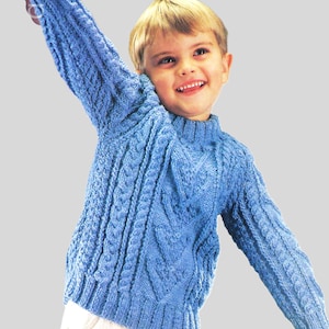 Könnte beinhalten: Ein blauer Strickpullover mit Zopfmuster. Der Pullover hat einen runden Ausschnitt und lange Ärmel.