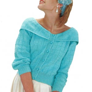 May include: A light blue knitted cardigan with a wide collar and button closure. The cardigan has a delicate stitch pattern and is worn with a white skirt.