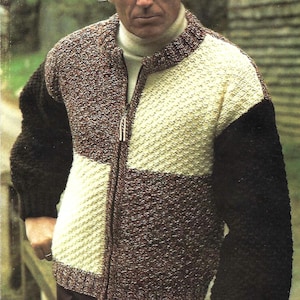 May include: A knitted zip-up cardigan with a colour-block design. The cardigan features a cream-coloured section, a brown section, and black sleeves. It is worn over a white roll neck.