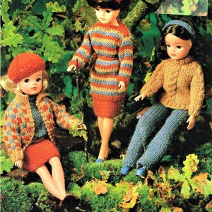 May include: Three knitted doll outfits in a woodland setting. The outfits include a striped dress, a sweater and pants, and a sweater and skirt.