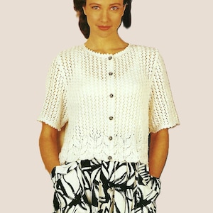May include: A white crocheted cardigan with a button-up front and short sleeves. The cardigan features a delicate openwork pattern and a scalloped hem.