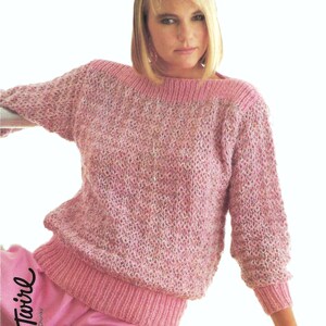 May include: A pink knitted jumper with a loose fit and a wide neckline. The jumper has a textured pattern and a ribbed hem.