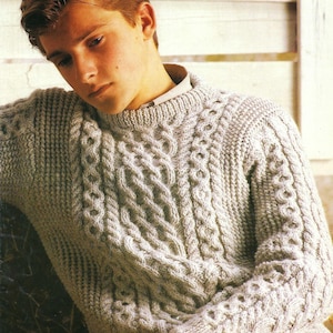 Puede incluir: Un suéter de punto de cable gris claro con cuello redondo.