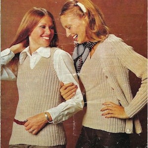 Puede incluir: Dos mujeres con suéteres de punto. Una mujer lleva un chaleco de punto beige con una camisa blanca debajo. La otra mujer lleva un suéter de punto beige con una bufanda de lunares blancos y marrones. Ambos suéteres tienen una textura acanalada.