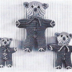 Puede incluir: Tres osos de peluche tejidos de diferentes tamaños, todos vestidos con pijamas a rayas grises y blancas. El oso más grande está en el centro, y el oso más pequeño está a la izquierda.