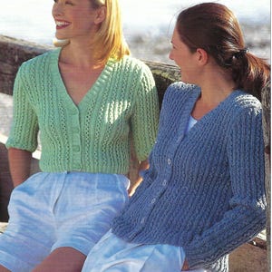 Peut inclure: Deux personnes portent des cardigans tricotés. L'un est vert clair à manches courtes, l'autre est bleu à manches longues. Les deux ont un col en V et une fermeture boutonnée. Ils sont associés à des shorts blancs.