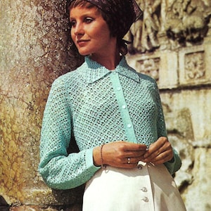 Puede incluir: Un atuendo vintage que presenta una rebeca de ganchillo azul claro con cuello y cierre de botones, combinada con una falda blanca con detalles de botones. Un pañuelo estampado completa el look, evocando un estilo de moda retro.