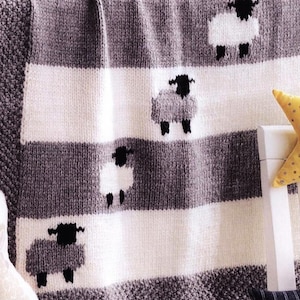 May include: A knitted baby blanket with a striped pattern in white and grey. The blanket features four black and white sheep appliques.